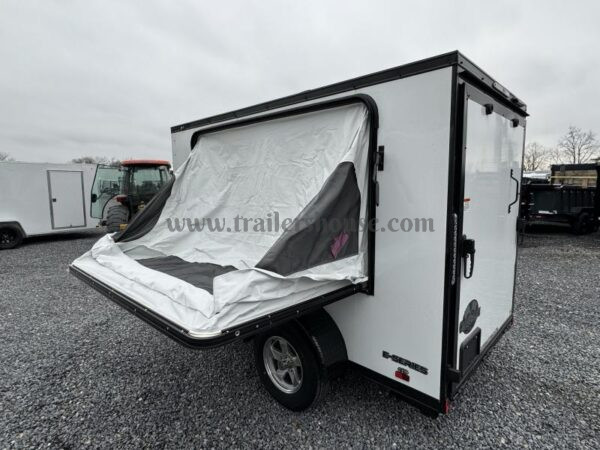 2024 Cargo Mate 5.5x10' Enclosed Toy Hauler Trailer 2990# GVW * TOY HAULER * FOLD OUT BED * WHITE BLACKOUT * SLANT V-NOSE * ALUMINUM WHEELS * .030 SCREWLESS EXTERIOR * REAR SPOILER * PLYWOOD FLOORS/WALLS * TABLE * MAX AIR COVER * EXTRA HEIGHT